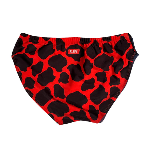 Red swim briefs with black cow print pattern on a white background